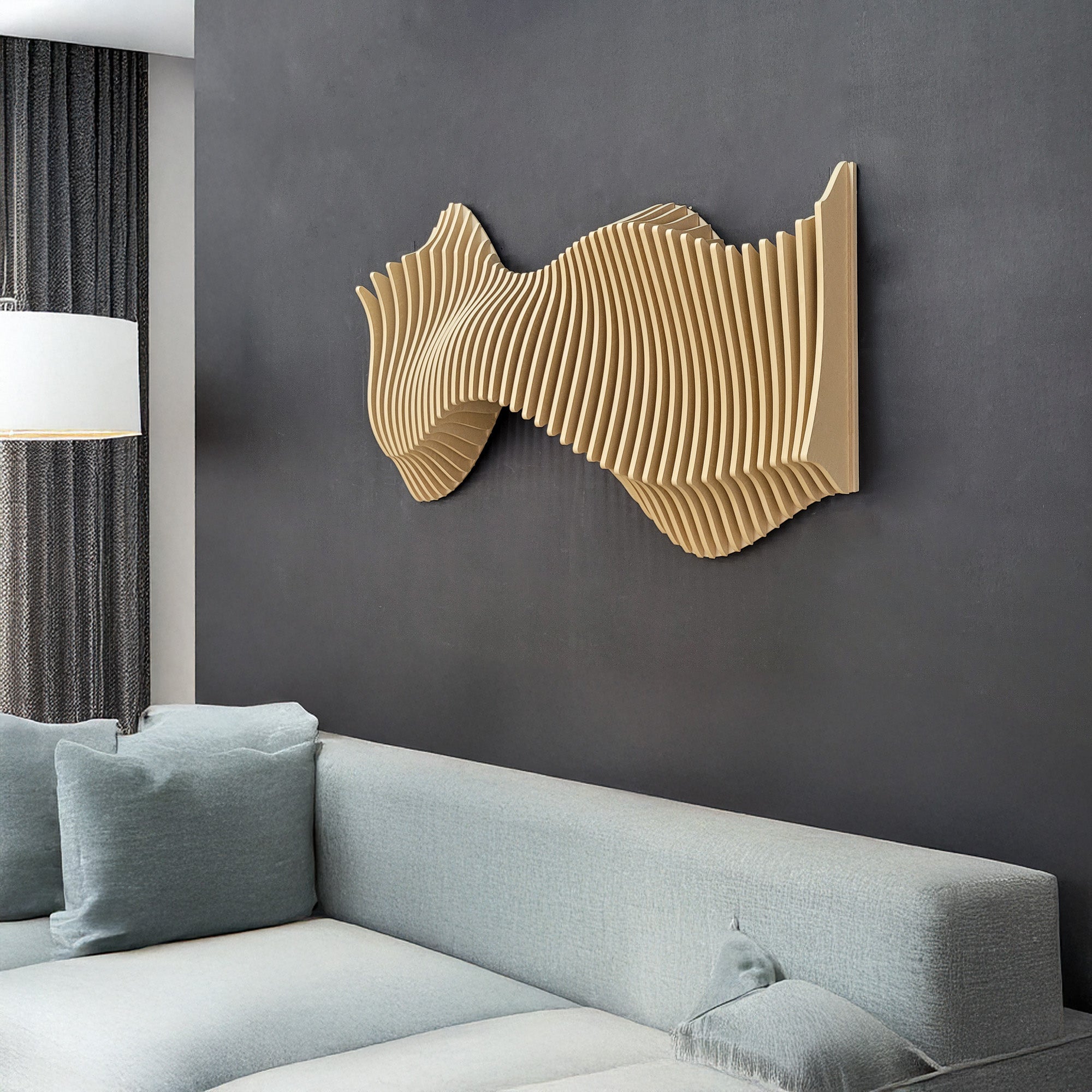 A 3D wall art piece with a wavy, curved design mounted on a dark wall above a light-colored couch, with a lamp and a window in the background.